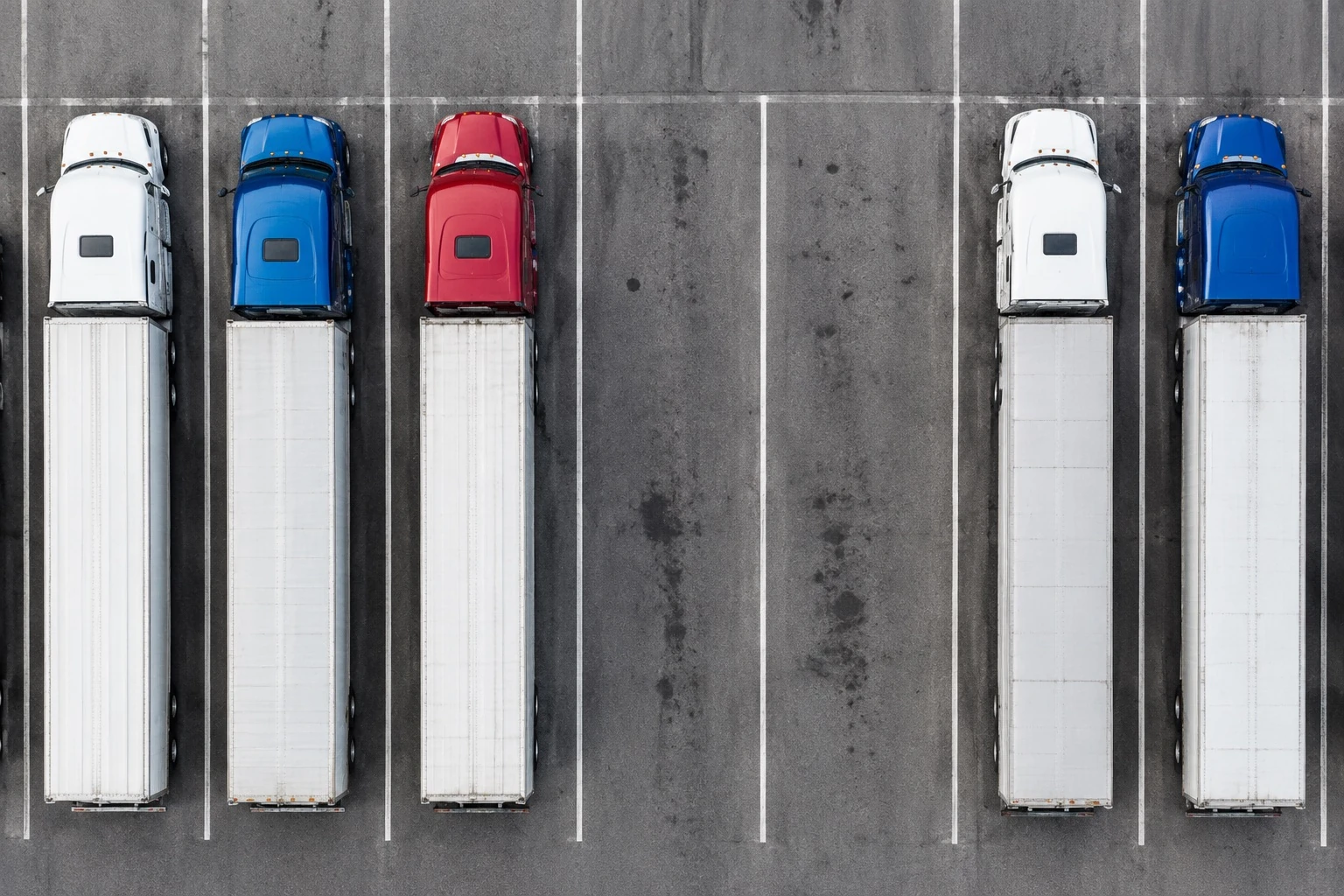 Illustrative vertical overhead view of semi trucks parked in marked bays, with empty bays visible.